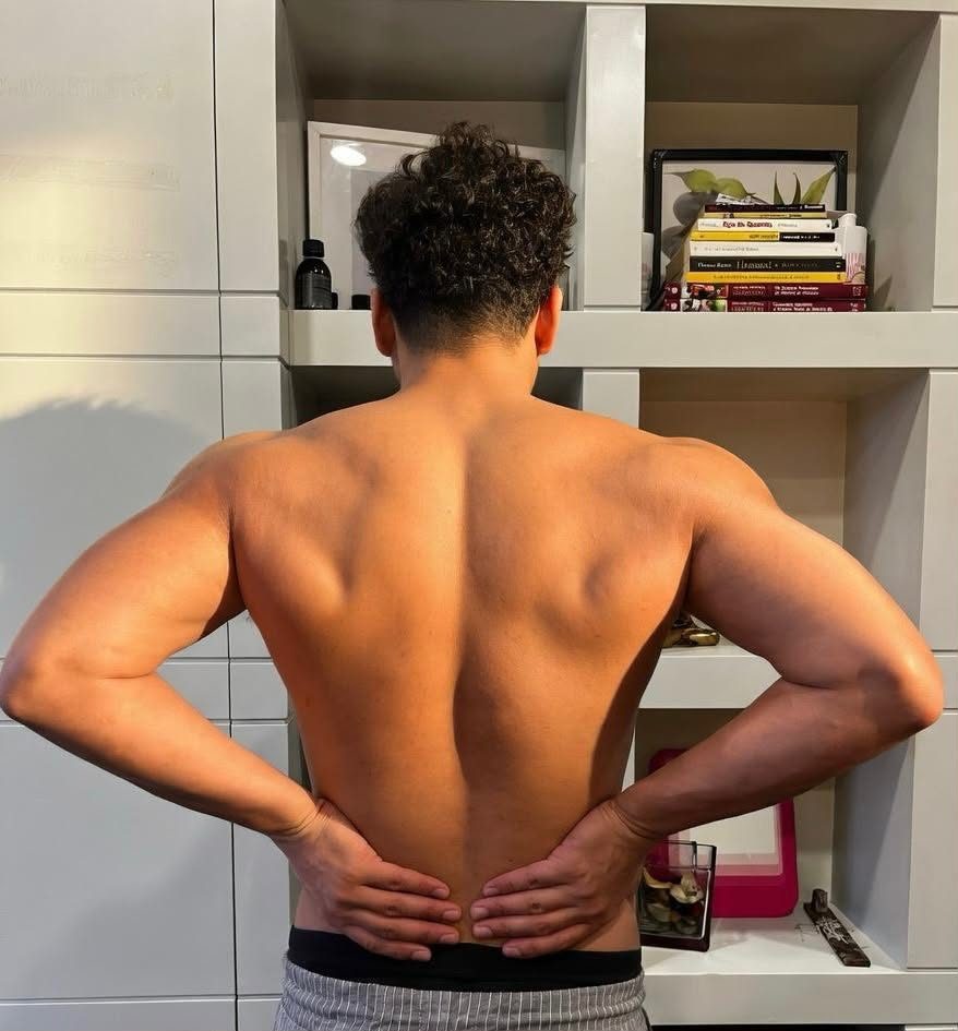 A man standing in the studio, hands resting on his lower back